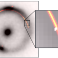 Samengesteld beeld van de infraroodemissie (zwart-wit) en de radio-emissie (kleur) van een donker object op tien miljard lichtjaar van de aarde (in de opening van de heldere boog rechts). © Keck/EVN/GBT/VLBA