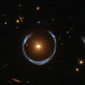 De zwaartekrachtlens die het Kosmische Hoefijzer wordt genoemd. Het pas ontdekte ultra-zware zwarte gat bevindt zich in het centrum van het oranje sterrenstelsel. © NASA/ESA