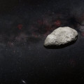 Artist’s impression van een kleine, onregelmatig gevormde planetoïde tegen een hemelachtergrond. © N. Bartmann (ESA/Webb), ESO/M. Kornmesser and S. Brunier, N. Risinger (skysurvey.org)