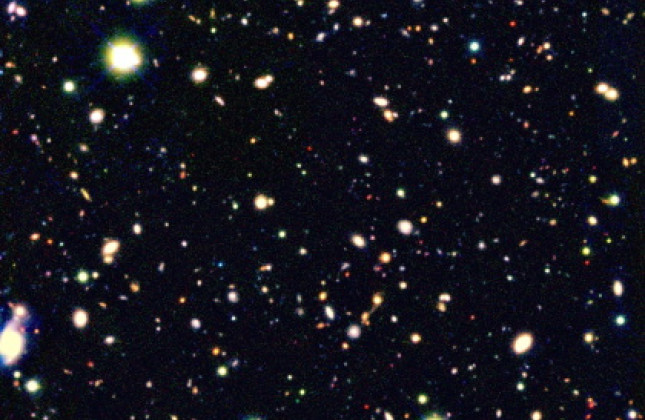 Een kleurenmontage van de meest gevoelige opname van het heelal, gemaakt door Ivo Labbé. De foto laat veel rode sterrenstelsels zien. Drie daarvan zijn linksboven uitvergroot weergegeven. Dit zijn relatief oude sterrenstelsels in een jong heelal. Dit bee