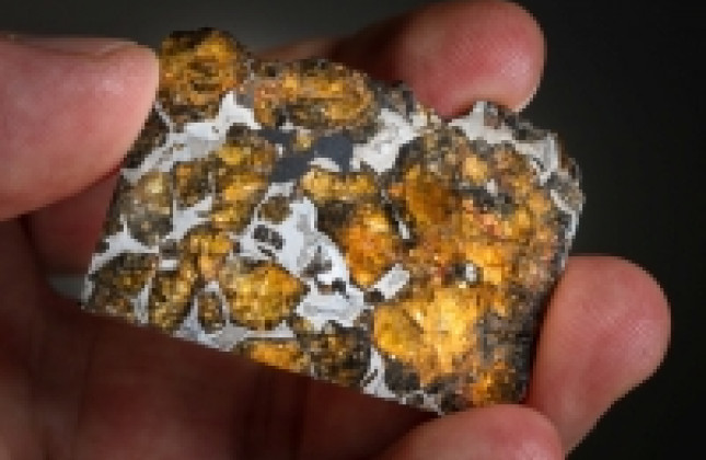 Olivijnkristallen in een meteoriet die op aarde gevonden is. De olivijnkristallen - geel en tussen 1 mm en 1 cm groot - worden bijeen gehouden door een mengeling van ijzer en nikkel. Dit soort meteorieten, pallasieten genoemd, komen uit ons zonnestelsel e