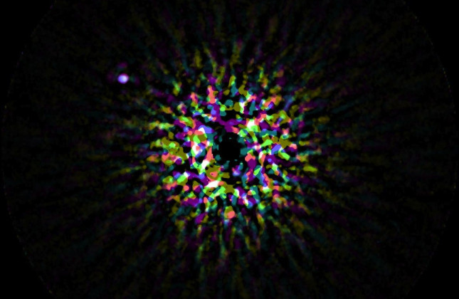 Op deze afbeelding is de planeet Kappa Andromeda b zichtbaar aan de linkerkant doordat een groot deel van het sterlicht van de centrale ster uit de foto is gefilterd. De stippelhalo in het centrum is het overgebleven sterlicht dat willekeurig is verdeeld.