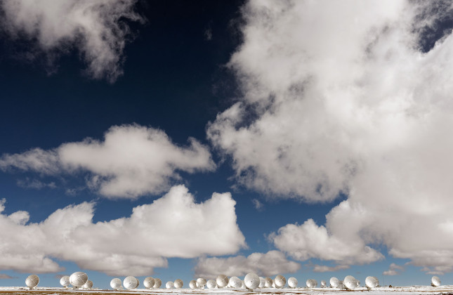 Een prachtige foto van ALMA. De wolken zijn erg fotogeniek, maar laten zien dat er veel meer vocht in de lucht zit dan normaal.  Credit: Philipp Weber-Bertram, (Cagefish) for Legacy of Gods, (legacyofgodsthemovie)