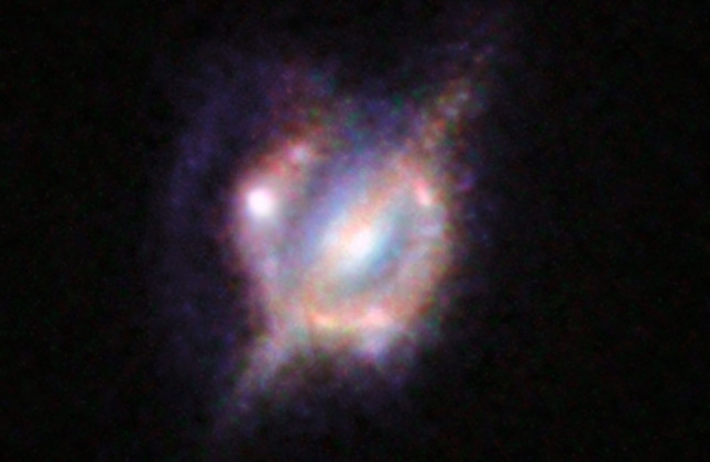 Samensmeltende sterrenstelsels in het verre heelal, gezien door een zwaartekrachtslens. Credit: ESO/NASA/ESA/W. M. Keck Observatory