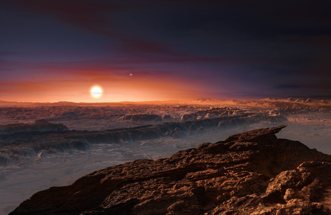 Deze artistieke weergave toont een blik op het oppervlak van de planeet Proxima b die rond de rode dwergster Proxima Centauri draait. Proxima Centauri is de dichtstbijzijnde ster vanaf ons zonnestelsel. Rechtsboven Proxima Centauri is de dubbelster Alpha 