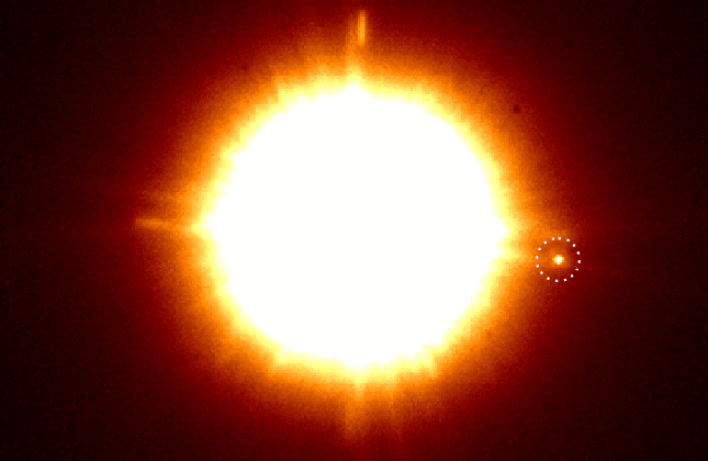 De dubbelster CS Cha met daarbij in de gestippelde cirkel de nieuw ontdekte begeleider. Met een muisklik wordt een afbeelding zichtbaar die gemaakt is met speciale polarisatiefilters die stofschijven en exoplaneten tonen. De begeleider lijkt een eigen sto