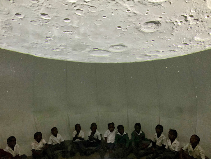 Namibische kinderen kijken in het mobiel planetarium van NOVA naar een projectie van de maan.