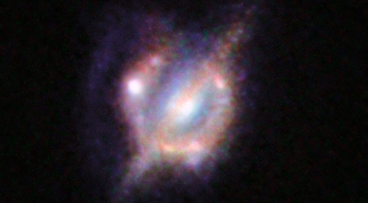 Samensmeltende sterrenstelsels in het verre heelal, gezien door een zwaartekrachtslens. Credit: ESO/NASA/ESA/W. M. Keck Observatory