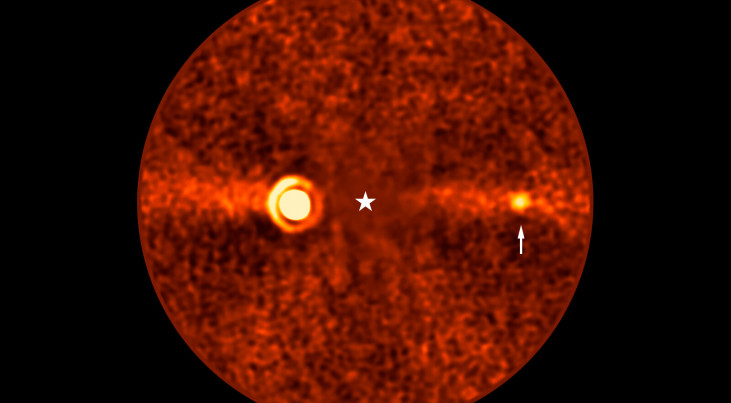 De ontdekte planeet Bèta Pictoris d (bij de witte pijl) op een opname van de Very Large Telescope. Het licht Bèta Pictoris is geblokkeerd (de witte ster). Links is de planeet Bèta Pictoris b zichtbaar. (c) ESO/B. Sutlieff, M. Bonse et al.
